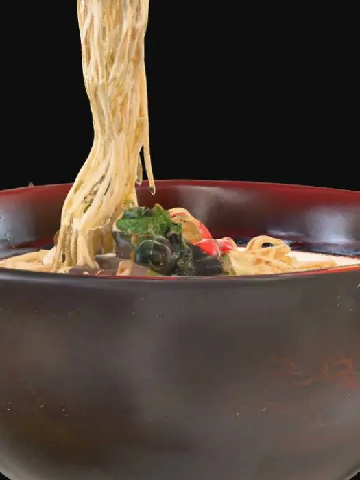 3D model for This 3D model shows a deep ceramic bowl filled with steaming vegetable ramen. The bowl is round and glossy, glazed in dark charcoal black with a subtle red rim, giving it a traditional Japanese look. Inside, a rich golden broth shimmers with oily highlights, topped with tender curled noodles that appear slightly wet and glistening. Floating on the surface are fresh vegetable toppings: bright green bok choy leaves, sliced carrots, crunchy bean sprouts, and thin rings of spring onion. A pair of glossy wooden chopsticks rests across the rim, adding authenticity. PBR textures enhance ceramic shine, soft vegetable surfaces, subtle steam effects, and liquid transparency, making the ramen appear warm, appetizing, and lifelike.