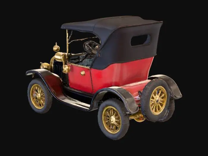 3D model for a vintage automobile from the early 20th century with a black folding canvas roof, a red body and black fenders, brass fittings and prominent front lights; the wheels are wire-spoked with yellow rims and the vehicle is moving on a textured surface resembling snow or ice