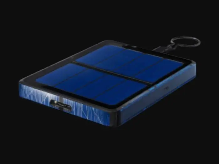 3D model for A sleek, portable solar charger with a thin, rectangular design, rounded edges, and a matte black aluminum body. The top features deep blue solar panels with a reflective glass layer. The sides have USB-C, USB-A ports, and an LED battery display. A foldable aluminum kickstand allows for angling, and a carabiner hook adds portability. The SunPod logo glows green when charging. The model has realistic textures, soft shadows, and accurate details
