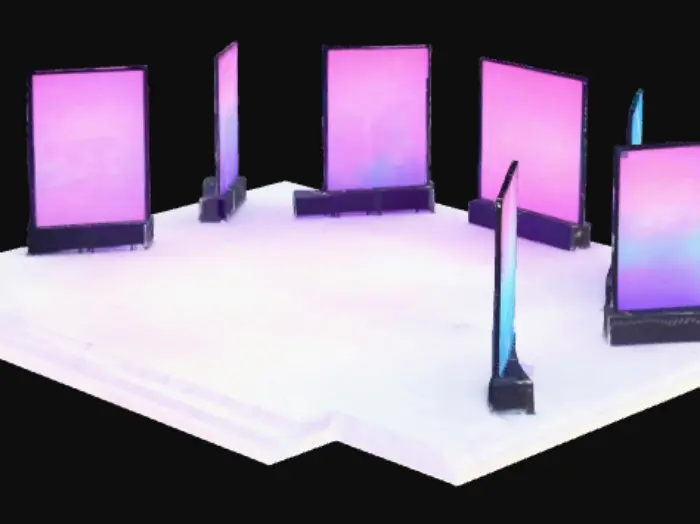 3D model for Wide shot of an outdoor night festival stage, with five glowing digital screens arranged as an art installation. A large crowd of people in front, seen as dark silhouettes. Bright colorful light beams shoot into the night sky, with haze and atmospheric depth, cinematic perspective.