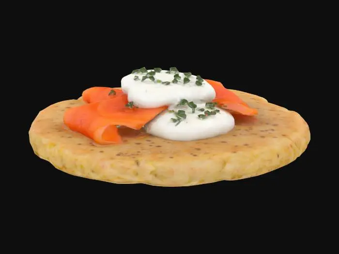 3D model for A silver dollar-sized buckwheat pancake, soft and speckled with a matte brown surface and crisp edges. Topped with a ribbon of glossy smoked salmon (translucent orange-pink), a dollop of crème fraîche (creamy white with soft peaks), and a sprinkle of finely chopped chive.