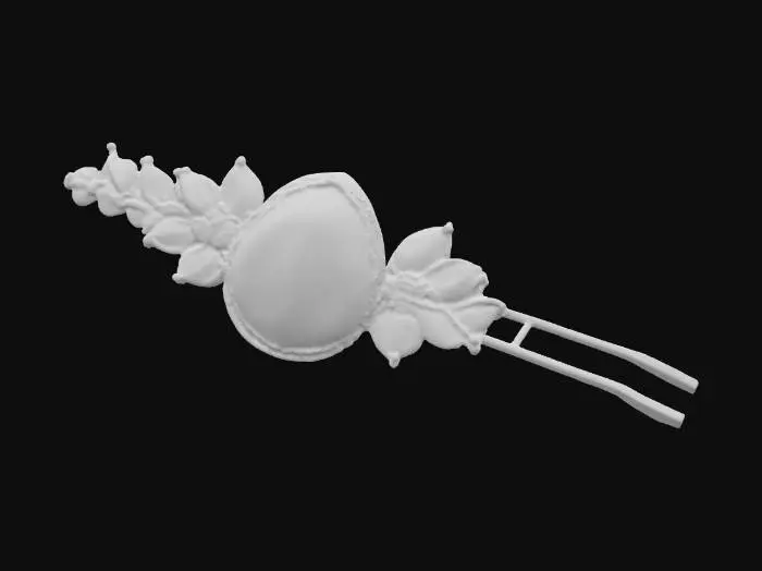 3D model for A long, slender hair pin, characteristic of Victorian elegance, features a silver body intricately embossed with floral motifs. The head of the pin is adorned with a large, teardrop-shaped mother of pearl piece, exhibiting a creamy white color with faint pink and green overtones. It is framed by a delicate border of minute, square-cut emeralds and tiny, round sapphires, creating a captivating sparkle.