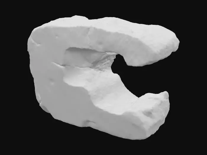 3D model for A broken sandstone rib segment, presenting a distinct missing chunk on one end, revealing the raw, fractured interior of the rock. The remaining edge around this void features a jagged, fractured lip, indicating natural breakage and erosion. Despite the damage, its layered sedimentary strata maintain a consistent direction, suggesting its origin from a larger, continuous formation. Composed of granular sandstone, it exhibits warm ochre and reddish-brown tones, with a rough, weathered texture across its fragmented form.