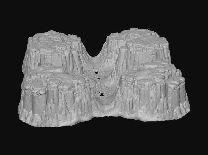 3D model for Eine ausgedehnte, felsige Landschaftsbasis mit sanften Erhebungen und Vertiefungen, die ein weites Tal formen. Im Hintergrund erhebt sich eine majestätische Bergkette mit schroffen, grauen Gipfeln, deren Felsflächen eine raue, erodierte Textur aufweisen. Der Vordergrund ist durch ein tiefes Tal gekennzeichnet, das von einer markanten, gewundenen Spalte durchzogen wird, deren glatte, ausgewaschene Kanten auf zukünftiges Wasser hindeuten. Die Erdoberfläche zeigt erdige Brauntöne und Grüntöne, durchsetzt mit kargen Felsen.