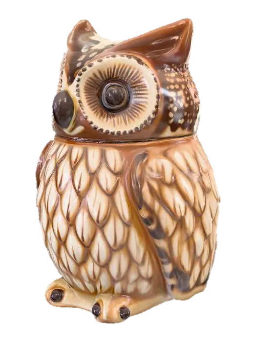 3D model for A charming, small trinket jar is meticulously crafted to resemble a plump owl. Made from smooth, glazed ceramic, its surface is cool and hard to the touch, painted in warm, earthy tones of brown and cream, with distinct feathery patterns. The owl's head is a separate piece, serving as the lid, designed to fit snugly onto the hollow body, creating a seamless appearance when closed. Its large, round eyes give it a wise, whimsical expression.