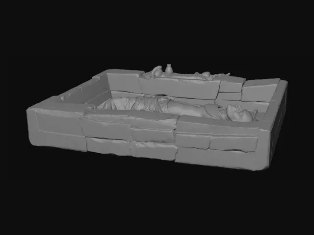 3D model for 3D Egyptian burial diorama shown as a cutaway desert tomb. A linen-wrapped body lies on its back in a shallow stone-lined chamber, with worn bandages revealing darkened preserved skin. Surrounding artefacts include a decorative broad collar necklace, simple bracelets, and a scarab amulet on the chest. Nearby are a small jar, a shabti figure, a broken pottery vessel, and food offerings. Sand layers and stone structure are visible in cross-section. Lighting is warm and soft with sandy tones. Style is realistic but simplified, like a museum display, designed for clear educational viewing and interpretation.