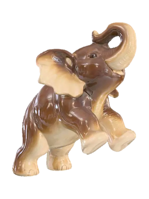 3D model for A playful ceramic elephant calf figurine, depicted with its trunk playfully raised and ears flapping, in a short, robust stance. Its rotund body and thick limbs are covered in a glossy two-tone glaze: a rich, dark brown on its back and outer legs, complemented by a soft, creamy beige on its belly and ear interiors. The smooth, cool sculpture feels solid and substantial, conveying youthful exuberance.