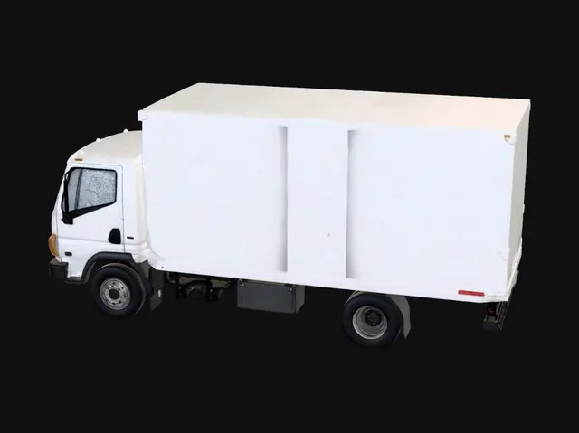 3D model for Rigid box delivery truck, intended as a semi-realistic simplified game asset. Main silhouette: a long rectangular cargo box fixed on a dark chassis, with a short front cab and a multi-axle layout: one front axle and a dual rear axle. Key recognizable elements: light grey/white cargo body, dark windshield and side windows, black horizontal grille, simple headlights, side mirrors, black tires with grey rims, rear double cargo doors, rear lights, and a rear bumper. Best Blender simplification: bevelled cubes for the cargo box, cab and chassis, cylinders for wheels, and thin panels for windows, grille, doors and lights. Avoid logos, open cargo, detailed interior, complex suspension, heavy textures, or excessive micro-details.